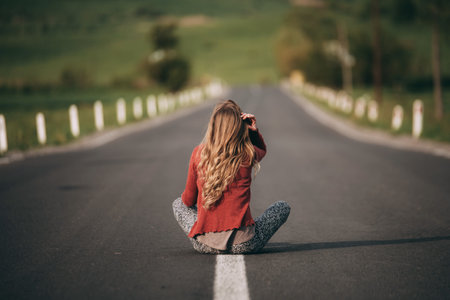 A young woman is sitting on the road and thinking about something.の写真素材
