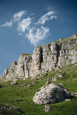 Mountain landscape with rocks and green grass under blue sky with cloudsの写真素材