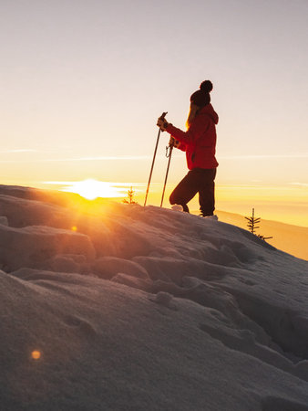 Silhouette of a woman hiker on top of the mountain at sunsetの写真素材