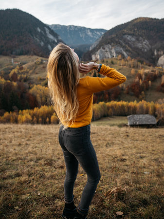 Beautiful young woman in a yellow sweater on the background of the mountains.の写真素材