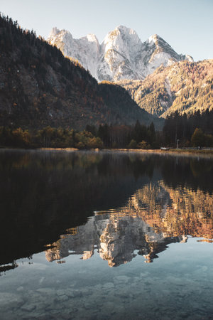 Autumn alpine landscape with reflection of snow-capped mountains in the lake