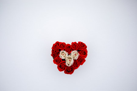 Heart made of red and white roses on fresh snow surface in a cold weather day. Flat lay, top view. Romantic outdoor concept for Valentine's day.の写真素材