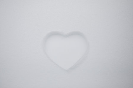 Heart shape on natural pure white soft snow surface in a cold weather day. Symbol of love in winter holiday season. Romantic outdoor concept for Valentine's day with copy space.の写真素材