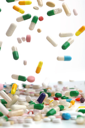 Capsules of colorful remedies falling in white background.の写真素材