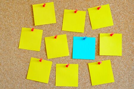 Cork board with multiple yellow and one cyan post-itの写真素材