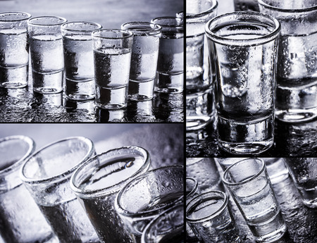 Vodka shot glass on wet black surface.の写真素材