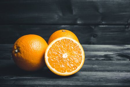 Orange cut into half, fruit section on black wooden table.の写真素材