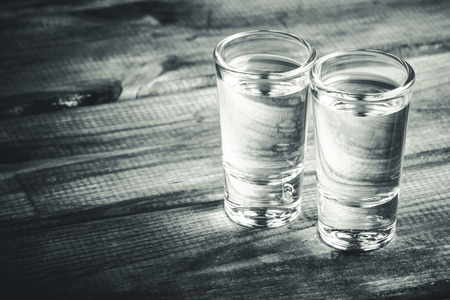 Vodka shots filled with alcohol on wooden black bar.の写真素材