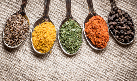 Spices on old metal spoons. Linen fabric background.の写真素材