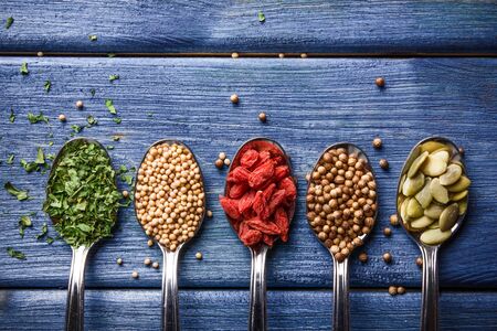 Spices in metal spoons on blue wooden table.の写真素材