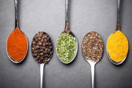 Different spices on metal spoons background.の写真素材