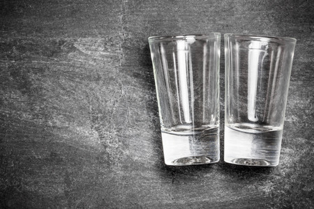 Vodka shot glass on black grunge surface.の写真素材