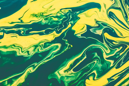Yellow and green paint flowing and mixing texture.の写真素材