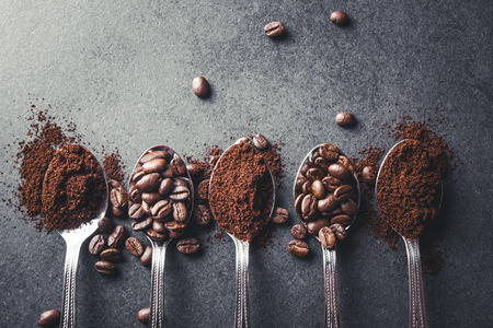 Coffee seeds on metal spoons black surface background.の写真素材