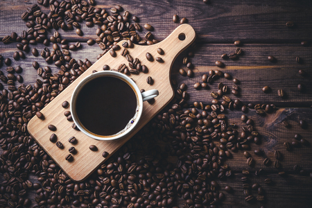 White coffee cup on wooden table with coffee seeds around.の写真素材