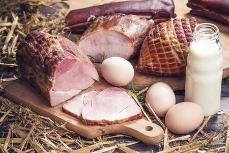 Rustic village food background. Homemade ham slices. Countryside eco eggs. Milk in bottle and hay all around.の写真素材
