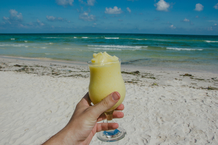 Male hand holding alcohol drink with beautiful weather on Phu Quoc beach island.