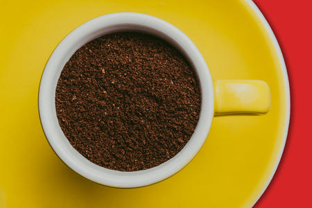 Espresso cup filled with coffee powder on yellow plate background.の写真素材