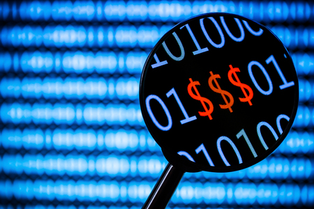 Magnifying glass zooming the red dollar sign. Computer screen with blurry binary code all around.の写真素材