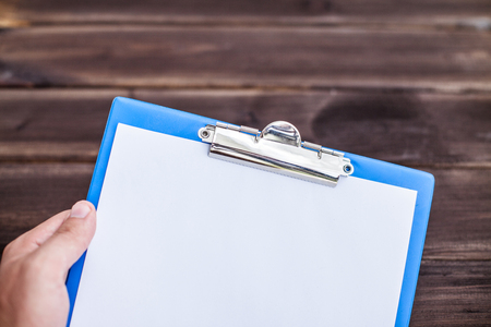 Holding empty copy space document writing over wooden desks table.の写真素材