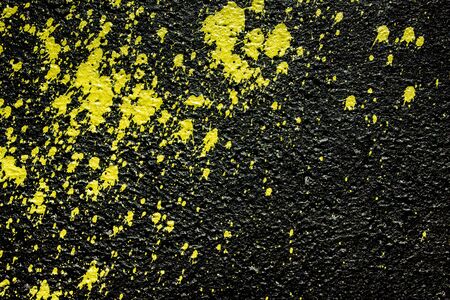 Yellow paint spray splash on black concrete wall background.の写真素材