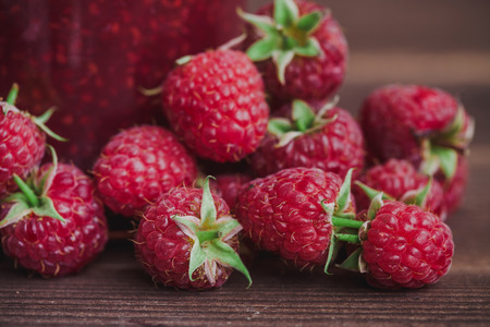 Vintage raspberry jam in glass jar isolated on wooden table.