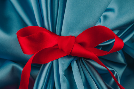 Red decorative ribbon on blue satin fabric.の写真素材