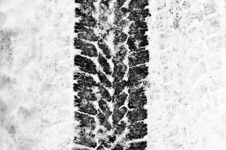 Black tire shape on snowy road background.の写真素材