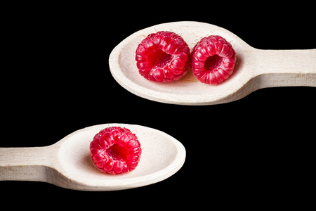 Pink vibrant raspberries on wooden spoon isolated on metal plate studio background.の写真素材