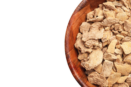 Ginger root pieces in wooden bowl. Kitchen spices container isolated on white studio background.の写真素材