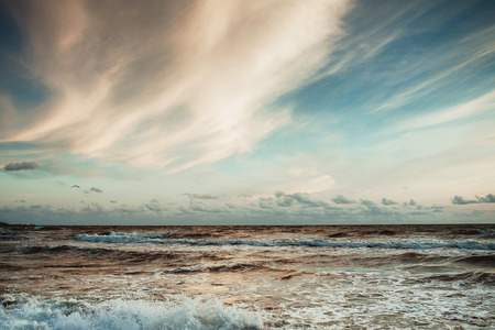 Beautiful sunset over wavy Baltic sea. Soft blue color and white yellow clouds on the sky.の写真素材