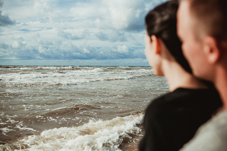 Baltic sea landscape. Stormy blue clouds on the sky. Couple watching wavy water.の写真素材