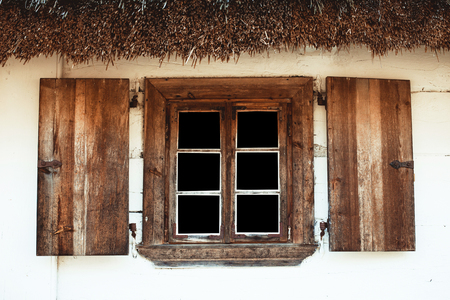 Wooden rustic window in small house with open shutters. Vintage white wood wall and empty copy space black glass window.の写真素材