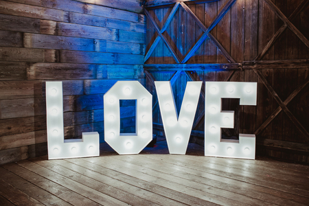 Wooden glowing love text letters. Rustic wedding dance floor lamp.の写真素材