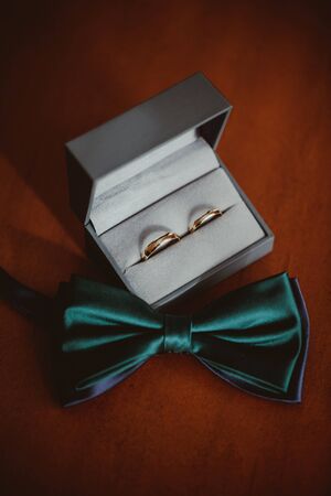 Elegant wedding accessories. Bowtie and golden rings background.の写真素材