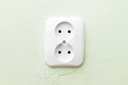 Simple white electrical socket on house wall closeup. Empty copy space electricity symbol...