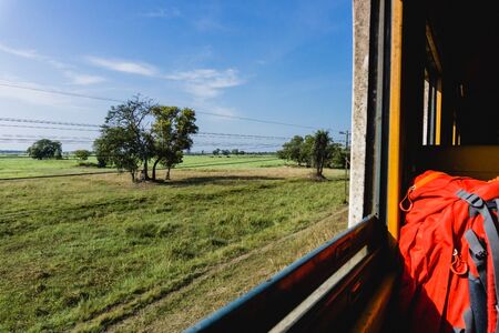 Open window train travel. Sunny summer in Thailand. Traveling with big backpack. Through the window...