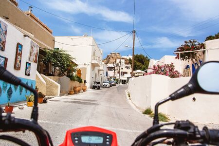 Quad bike ride. Santorini small street. Summer vacations in Greece travel with rental atv bike.