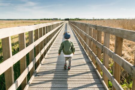 Boy walking long way in nature. Child exploring the world landscape. Parenthood and childhood...