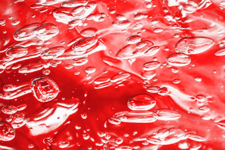 Red water background. Hair gel closeup backdrop. Abstract round bubble pattern. Fizzy liquid air drops texture.の写真素材