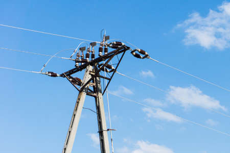 Energy transfer lines in Poland. Low voltage pole background. Small city electricity transmission line with glass and ceramic isolators. High old fashioned concrete construction.の写真素材
