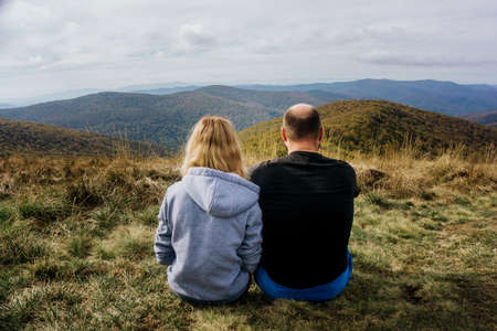 Couple travel background. Bieszczady National Park in Poland landscape. Autumn mountain trekking. Rural scenery. Hiking trail on the hill. Tourists watching the view. Friends planning their hike.の写真素材