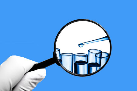 Hand in latex glove holding magnifying glass isolated on white background. Laboratory test tube....