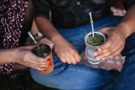 Yerba mate tea in bombilla. Special metal straw. Sout America popular hot drink. Couple drinking...