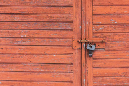 Wooden garage door. Metal padlock background. Peeling paint wood. Vintage rustic gate. Empty copy space grunge door texture.の写真素材