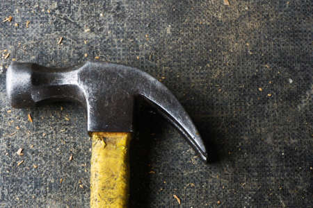 Grunge hammer background. Dirty and scratched iron hammer with yellow plastic handle.の写真素材