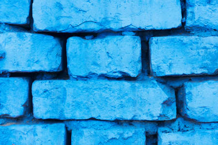 Blue paint brick wall background. Urban rustic closeup texture. Antique house exterior wall. Vintage abandoned building architecture. Destroyed and cracked brick construction.の写真素材