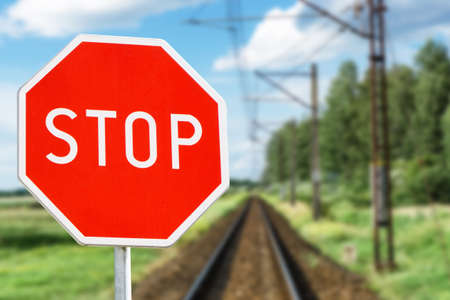 Stop sign on railroad tracks against blurred background, closeup. Space for textの写真素材