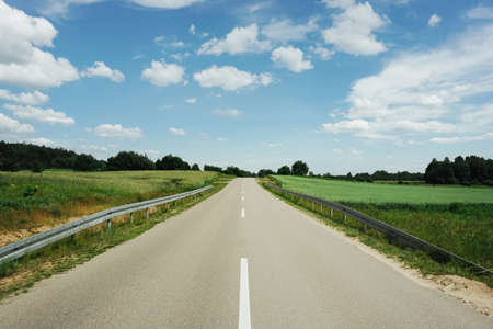 Asphalt road in the countryside with blue sky and white clouds.