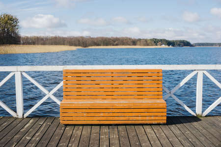 Wooden bench on a pier on the lake in the summer.